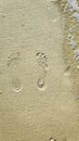 Close up of woman feet leaving footprints on golden sand beach, coast in sea ocean water. Vacation, travel and freedom Royalty Free Stock Photo