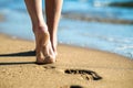 Close up of woman feet walking barefoot on sand leaving footprints on golden beach. Vacation, travel and freedom concept. People Royalty Free Stock Photo