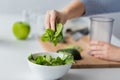 Close up of woman hand adding spinach to bowl