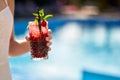 Close-up of woman hand cocktail glass decorated with mint, cherry and lemon. Female holding a drink near swimming pool Royalty Free Stock Photo