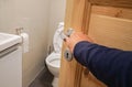 Woman hand with dark blue sweater open the toilet door handle Royalty Free Stock Photo