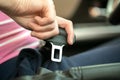 Close up of woman hand fastening seat belt while sitting inside a car for safety before driving on the road. Female driver driving Royalty Free Stock Photo