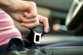 Close up of woman hand fastening seat belt while sitting inside a car for safety before driving on the road. Female driver driving Royalty Free Stock Photo