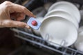 Close up of woman hand filling dishwasher tablet into open automatic stainless built-in dishwasher machine. Royalty Free Stock Photo