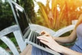 Close up woman hand fingers press laptop keyboard for remote work on sunny day, background of sunshine green palms in