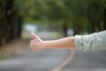 Close up woman hand hitchhiking at countryside road near forest,Alone travel or single traveller or hitchhiker concept Royalty Free Stock Photo