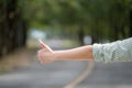 Close up woman hand hitchhiking at countryside road near forest,Alone travel or single traveller or hitchhiker concept