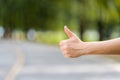 Close up woman hand hitchhiking at countryside road near forest,Alone travel or single traveller or hitchhiker concept