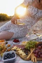 Close-up of a woman hand holding a bottle of wine and pouring an alcoholic drink into glasses outdoors. Picnic on the beach Royalty Free Stock Photo