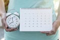 Woman hand holding calendar and alarm clock for planner, business, check for period schedule, healthy and travel plan