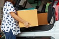 Close up on woman hand holding and carrying a cardboard box with stuffs moving into the car to relocation on moving day.