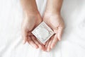 Close up woman hand holding condom lying on white bed, health care and medical concept Royalty Free Stock Photo