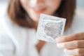 Close up woman hand holding condom lying on white bed, health care and medical concept Royalty Free Stock Photo