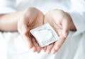 Close up woman hand holding condom lying on white bed, health care and medical concept Royalty Free Stock Photo