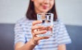 Close up of woman hand holding a drinking water in glass on sofa in house. Royalty Free Stock Photo