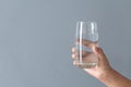 Close up woman hand holding a glass of pure water for dink with grey background, Health care concept Royalty Free Stock Photo