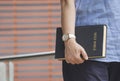 Close up woman hand holding holy bible while standing with blurred background in public area Royalty Free Stock Photo