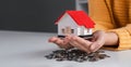 Close up woman is hand holding house model over coins stack. Concept for property ladder mortgage and real estate Royalty Free Stock Photo