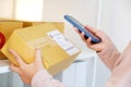 Close up of woman hand holding mobile phone and scaning product box for delivering to customer, online shopping, small business