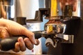 Close up woman hand holding portafilter, girl barista is grinding the roasted coffee beans into powder using coffee grinder at Royalty Free Stock Photo