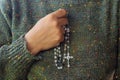 Close up of a woman hand holding a Rosary beads on her chest. Building deeper relationship with God concept. Praying The Rosary. Royalty Free Stock Photo