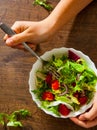 Woman hand holding various fresh mix salad leaves with tomato in bowl on wooden background on the fork Royalty Free Stock Photo