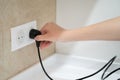 Close up Woman hand insert or pull out elecrticity plug in outlet on the wall