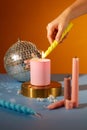 Close up of woman hand lighting candles on colorful background. Candles, pearls and a disco ball decorated on the table. Party Royalty Free Stock Photo