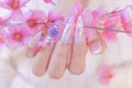 Close up woman hand manicure with long acrylic extension stiletto style painting sweet ombre pink glitter decorated with beautiful