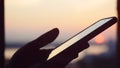 Close up of woman hand with mobile phone on blurred sunset city background Royalty Free Stock Photo