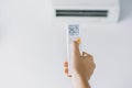 Close-up of woman hand operating air conditioner with remote control. Open air conditioning 25 degrees Royalty Free Stock Photo