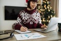 Close up of woman hand with pen in Santa hat making notes on paper document