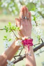 Close up woman hand with rings and bracelets in yoga mudra namaste gesture in front cherry blossom Royalty Free Stock Photo