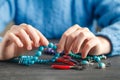 Close up of woman hand threading beads on drawstring to make artistic bead necklace or bracelet