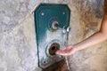 Close up of woman hand under running water from a fountain in the wall. Thirsty and water crisis concept