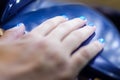 Close up of woman hand in UV or led lamp drying gel polish on her nails. Perfect manicure.