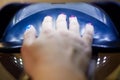 Close up of woman hand in UV or led lamp drying gel polish on her nails. Perfect manicure.