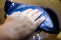 Close up of woman hand in UV or led lamp drying gel polish on her nails. Perfect manicure.