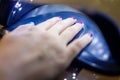 Close up of woman hand in UV or led lamp drying gel polish on her nails. Perfect manicure.