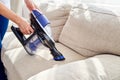 Close up of woman hand with vacuum cleaner, copy space. Woman cleaning sofa with vacuum cleaner. Household and spring-cleanig