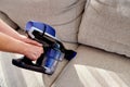 Close up of woman hand with vacuum cleaner, copy space. Woman cleaning sofa with vacuum cleaner. Household and spring-cleanig