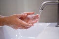 Close up of a woman hand washing with soap under the faucet with water in the bathroom inside the house. Concept of hand cleaning, Royalty Free Stock Photo