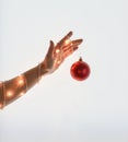 Close up of woman hand wrapped with string Christmas light holding Christmas rad ball on white background.