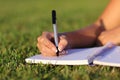 Close up of a woman hand writing on a notebook outdoor