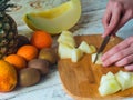 Close up woman hands cutting fresh melon with knife on wooden chopping board. Female cutting fruits Royalty Free Stock Photo