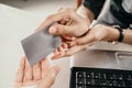 Close up of woman hands giving credit or debit card to man for transaction in office Royalty Free Stock Photo