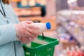 Close up of woman hands in gloves holding a shopping basket and choosing milk in a supermarket. Shopping during Royalty Free Stock Photo