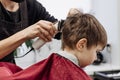 Close-up of woman hands grooming kid boy hair in barber shop. Royalty Free Stock Photo