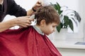 Close-up of woman hands grooming kid boy hair in barber shop. Royalty Free Stock Photo