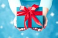 close up of woman hands holding christmas gift box over blue background Royalty Free Stock Photo